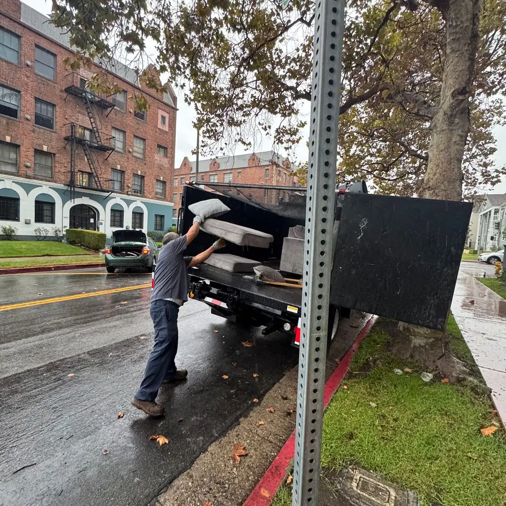 crew member loading old furniture into a pickup truck