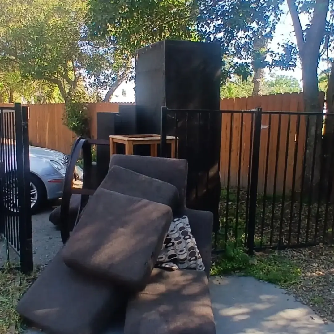 old couch and furniture by fence before pickup in Mango FL